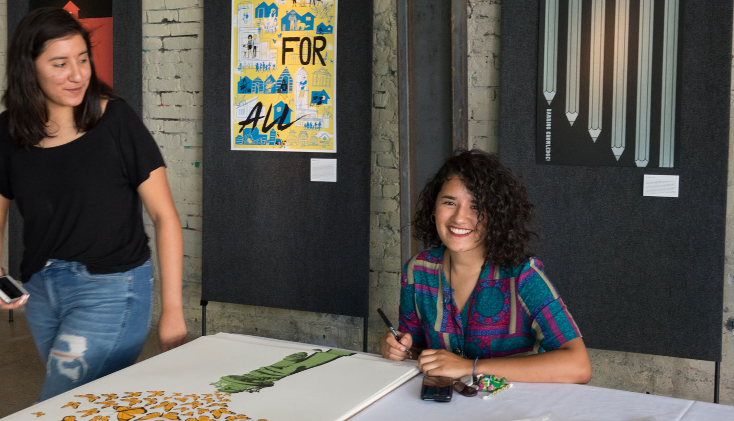 Artist Edith Valle signs copies of her poster. - Photo courtesy I Heart Justice